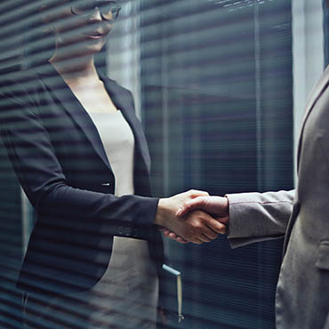 Shutterstock image (by Pressmaster): Close-up of two businesswomen shaking hands.