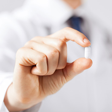 Shutterstock image (by Syda Productions): a singular pill being held by someone's hand.