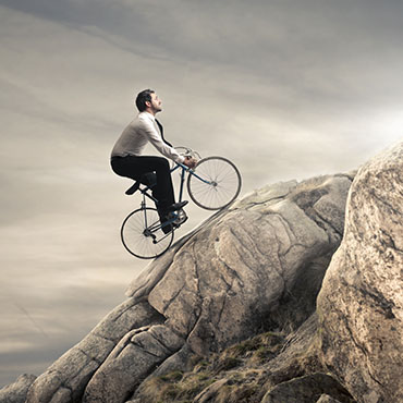 Shutterstock image: executive riding a bike up a mountain.